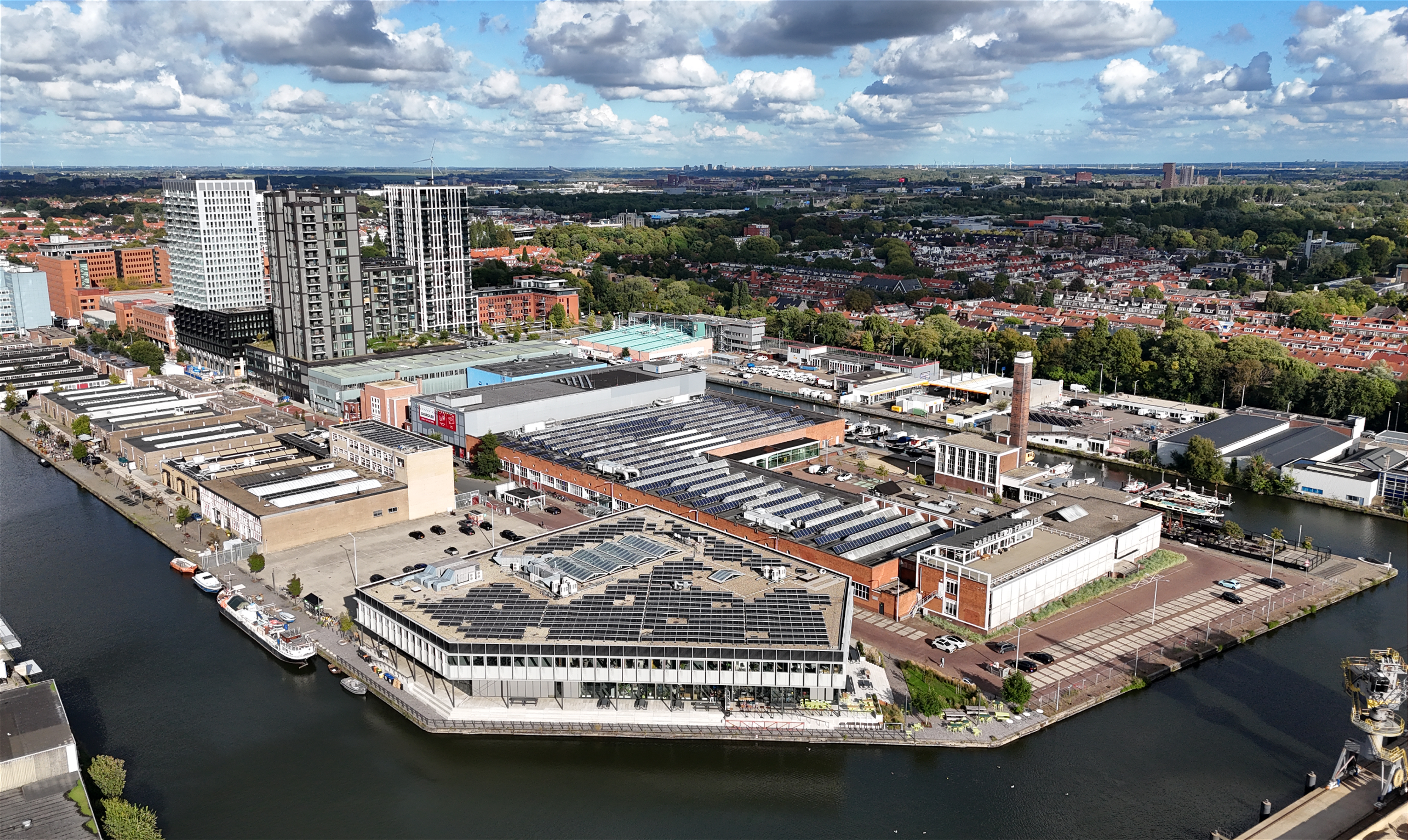 An aerial view of a waterfront campus and the surrounding city skyline